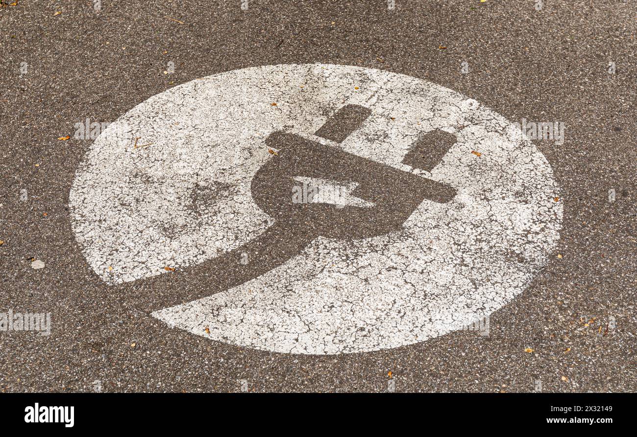 Ein Steckersymbol auf einem Parkplatz symobilisiert, das hier Elektroautos geladen werden können. (Rheinfelden, Schweiz, 13.04.2022) Stock Photo
