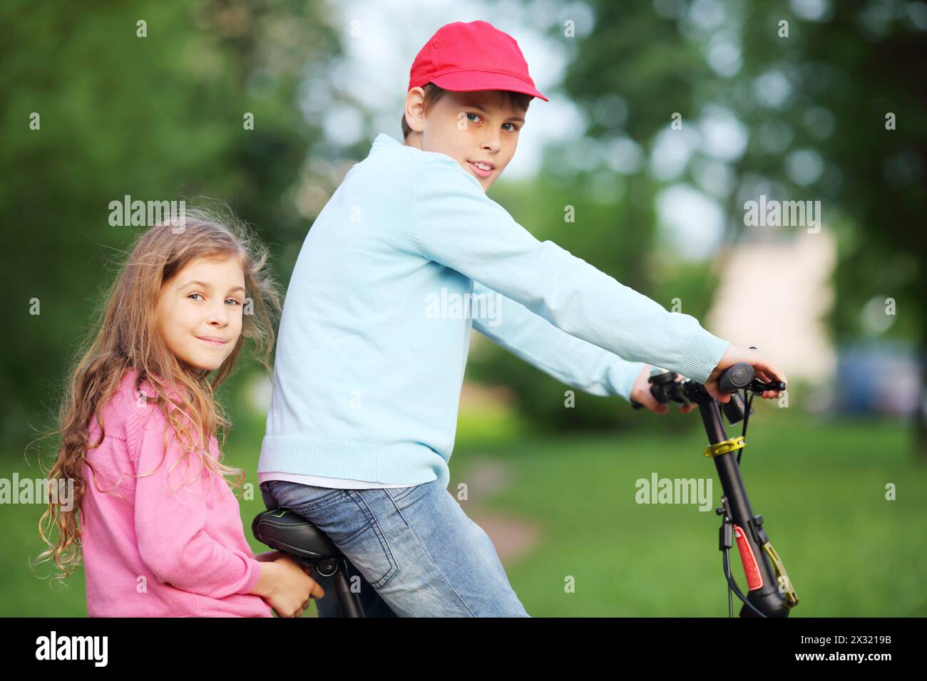 Happy brother and sister ride bicycle in park at summer day Stock Photo ...