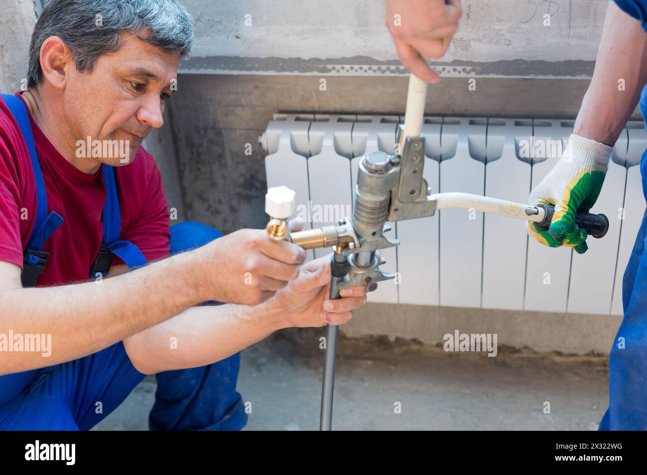 Two workers swaged pipe heating system in the apartment Stock Photo