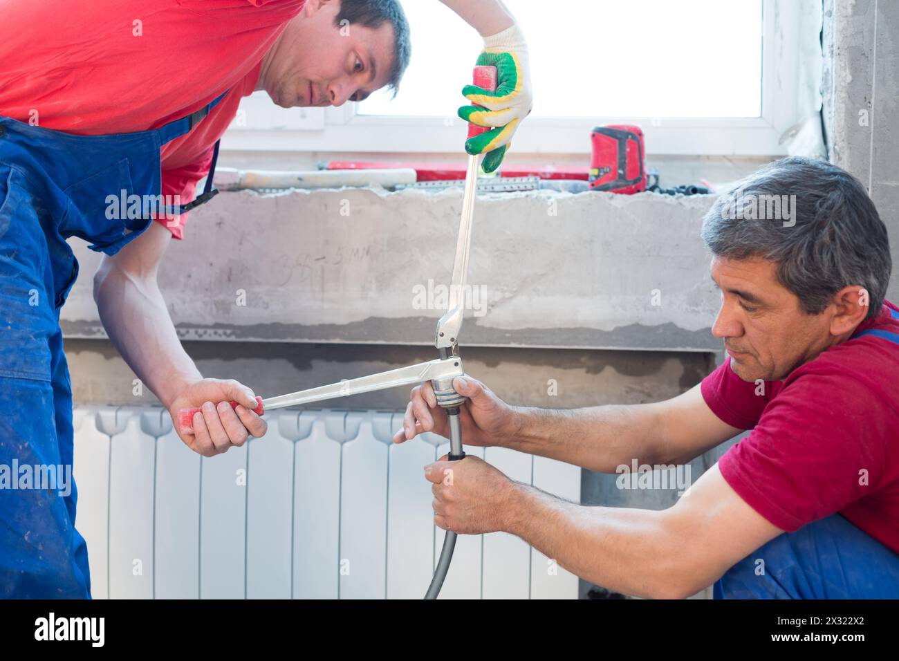 Workers prepare the pipes for the heating system crimping Stock Photo