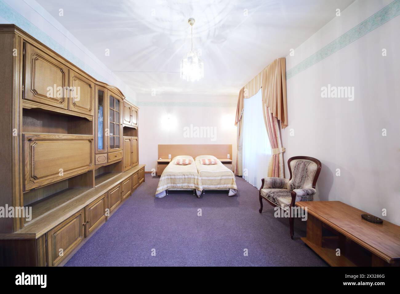 Light bedroom with a double bed, armchair and wall cabinet Stock Photo