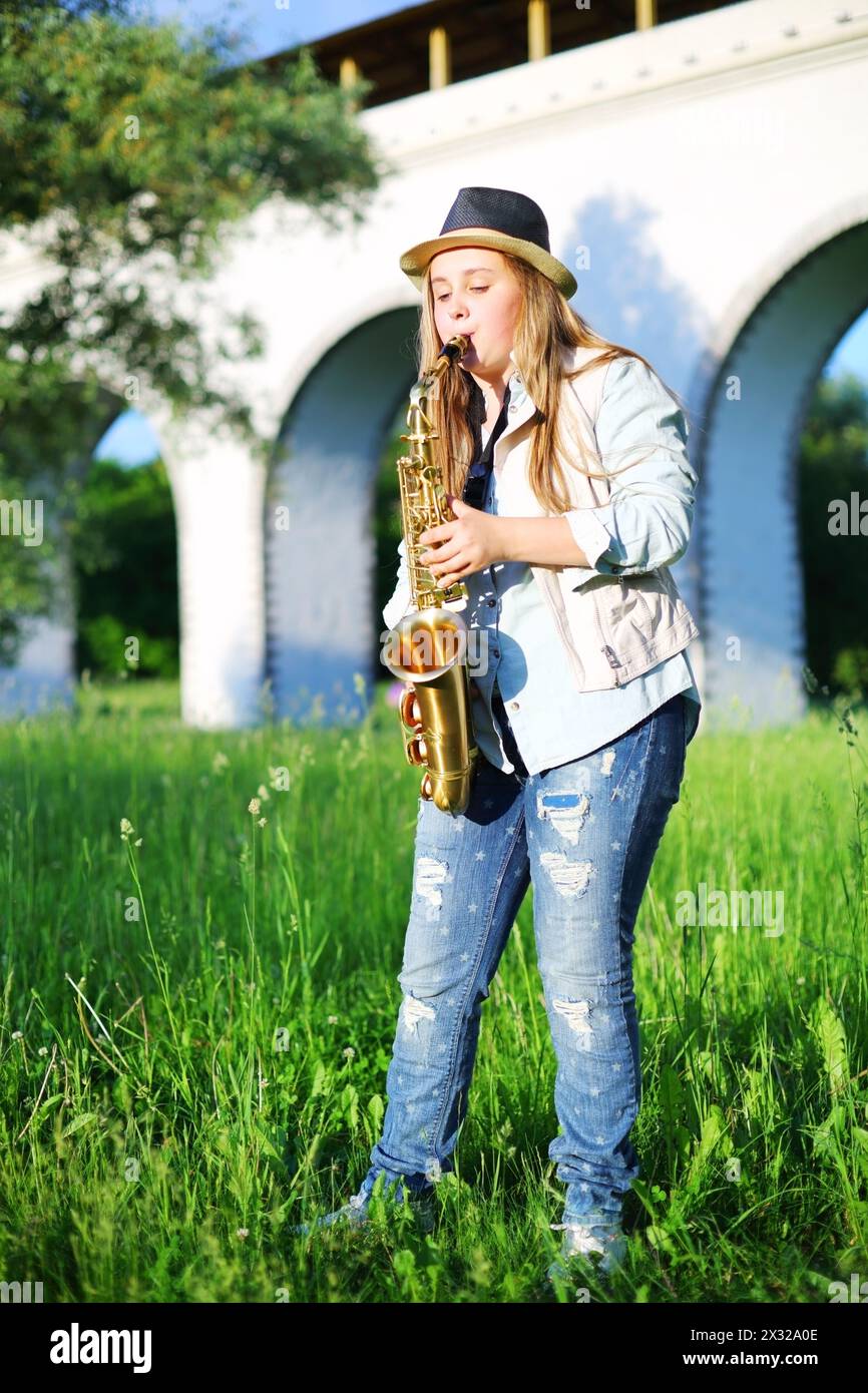 The girl in a hat playing the saxophone Stock Photo