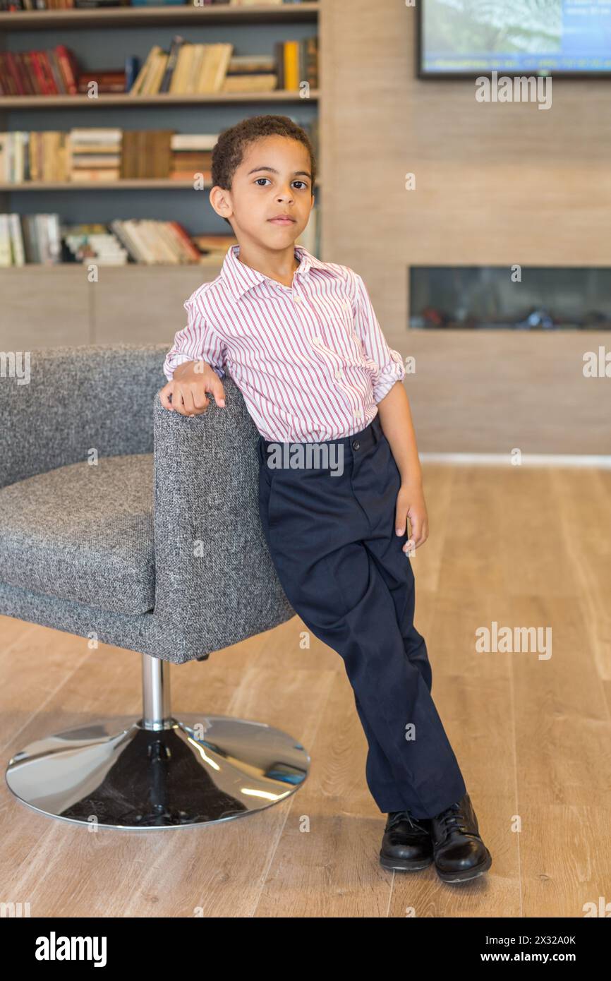 Boy in shirt standing in the business center of leaning on the chair Stock Photo