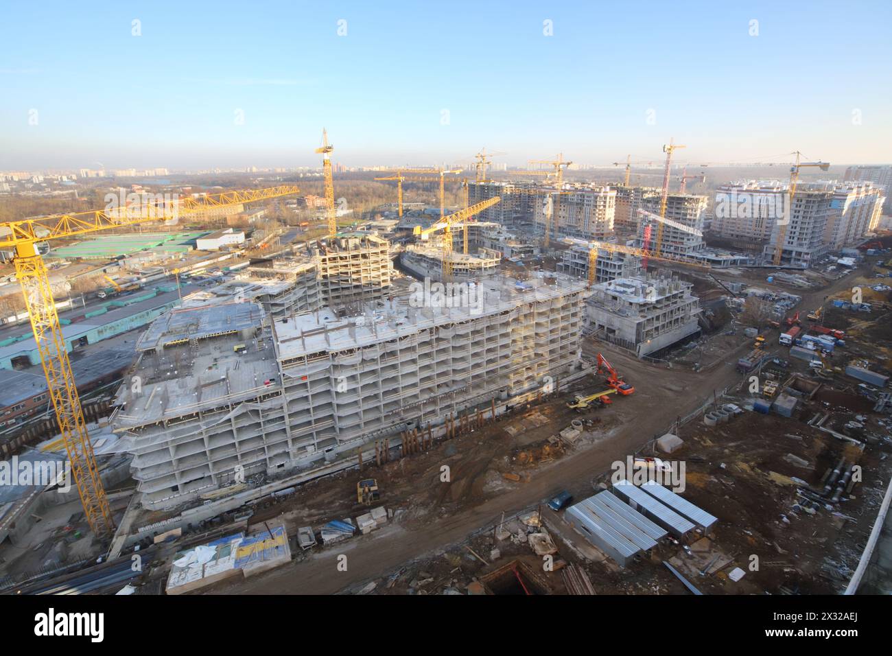 High multi-storey buildings under construction and yellow cranes at sunny day. Stock Photo