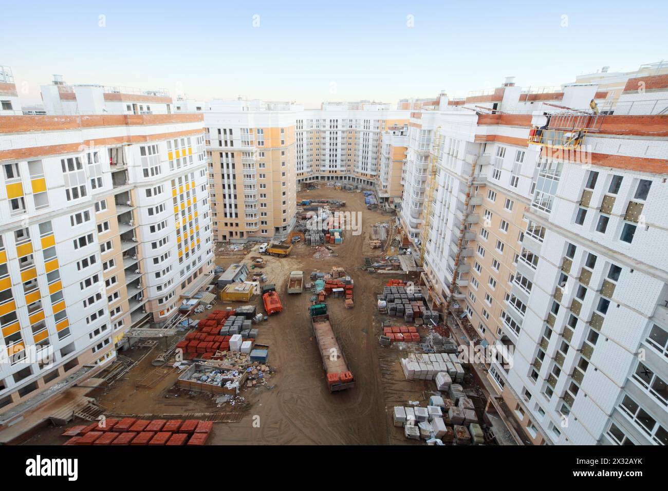 Multi-storey residential buildings under construction, trucks, bricks and other building materials at day. Stock Photo