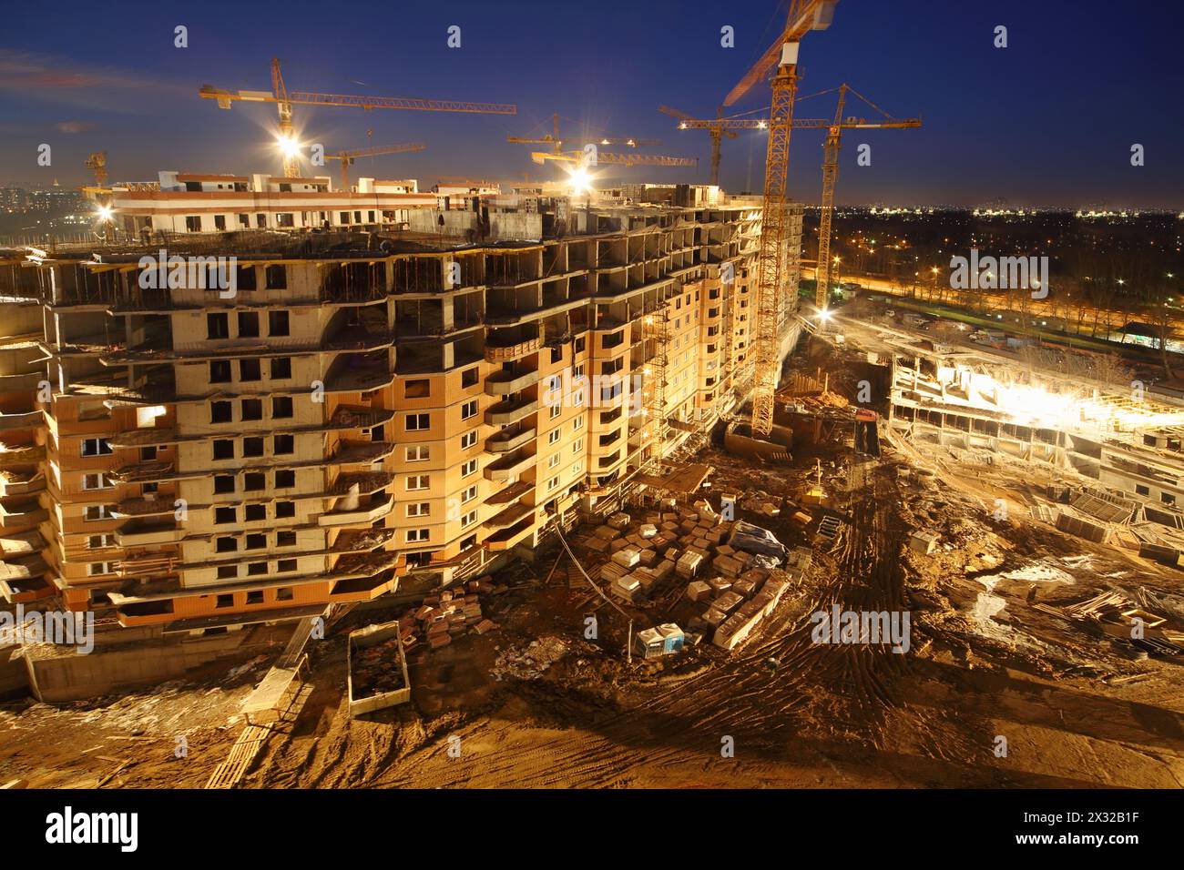 Lots of tower cranes build high-rise residential buildings at night. Stock Photo