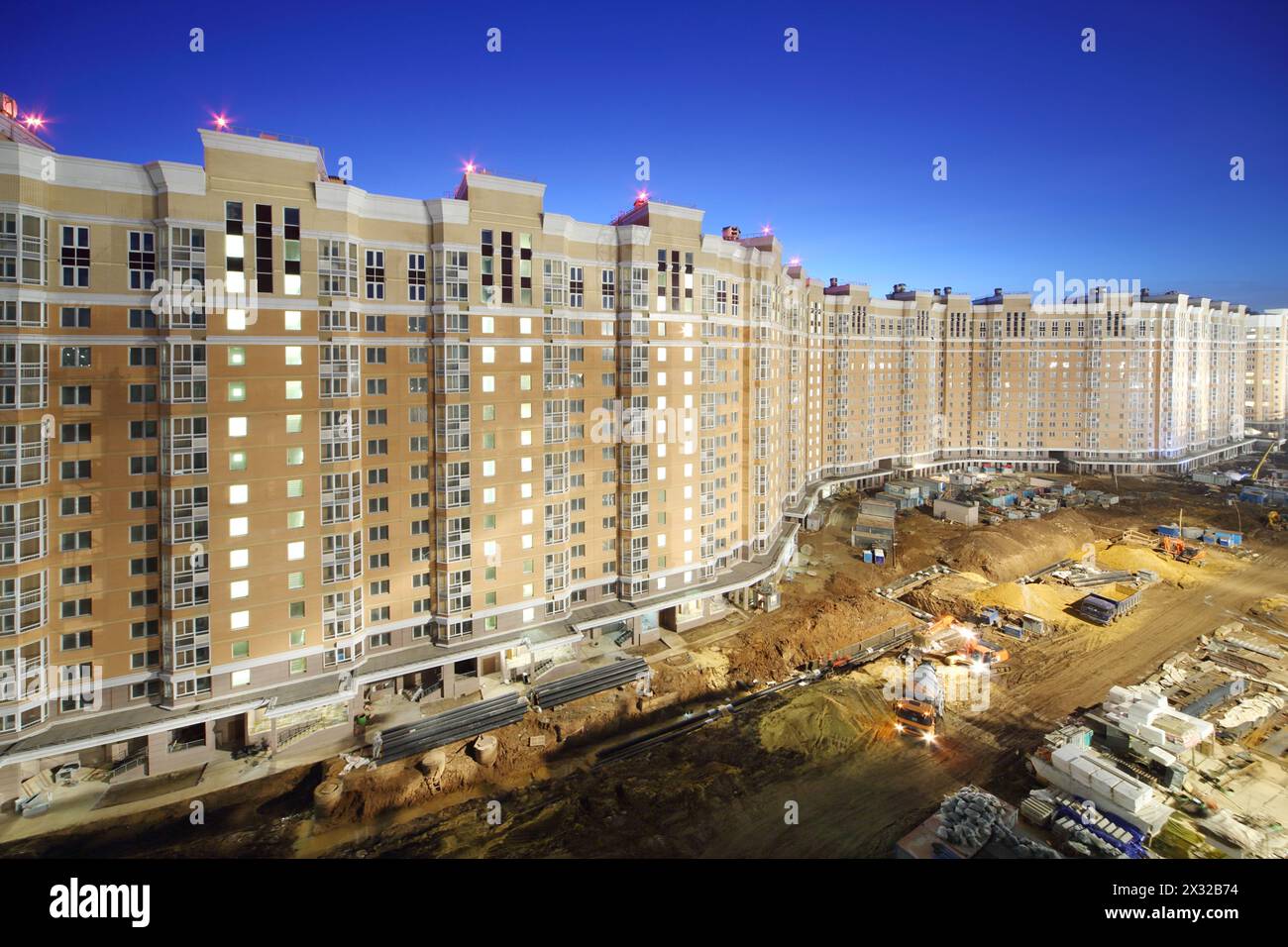 Long high multi-storey building under construction at night. Stock Photo