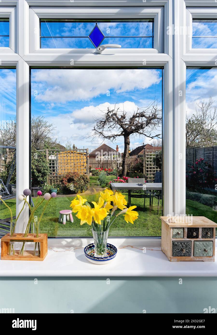 A view of a private garden as seen through the windows of a conservatory on a sunny spring day, Shepperton England UK Stock Photo