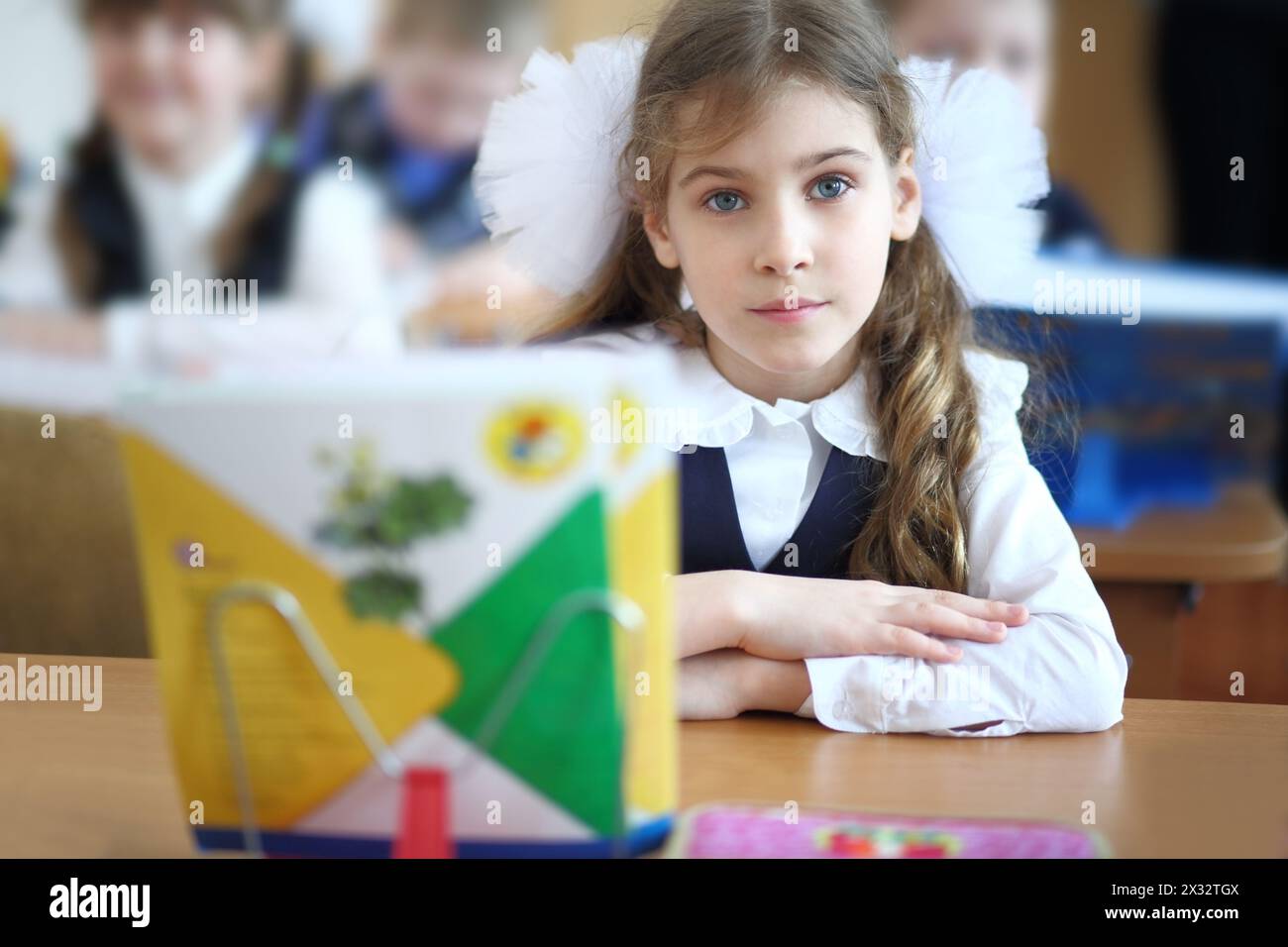 Schoolgirl sits at a school desk with notebooks on a stand in the ...