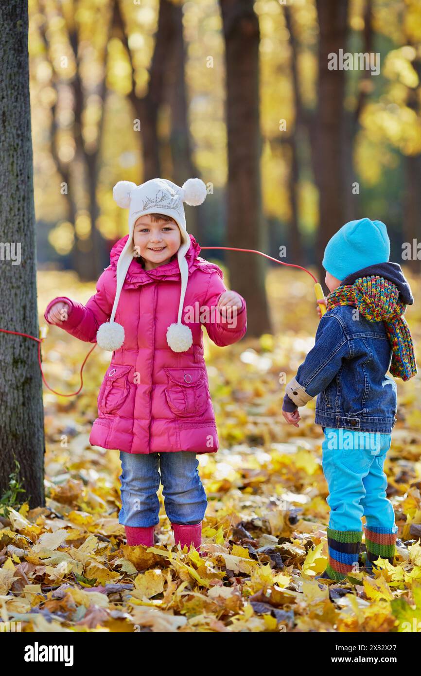 Girl jumps over rope which one end is attached to tree trunk and ...