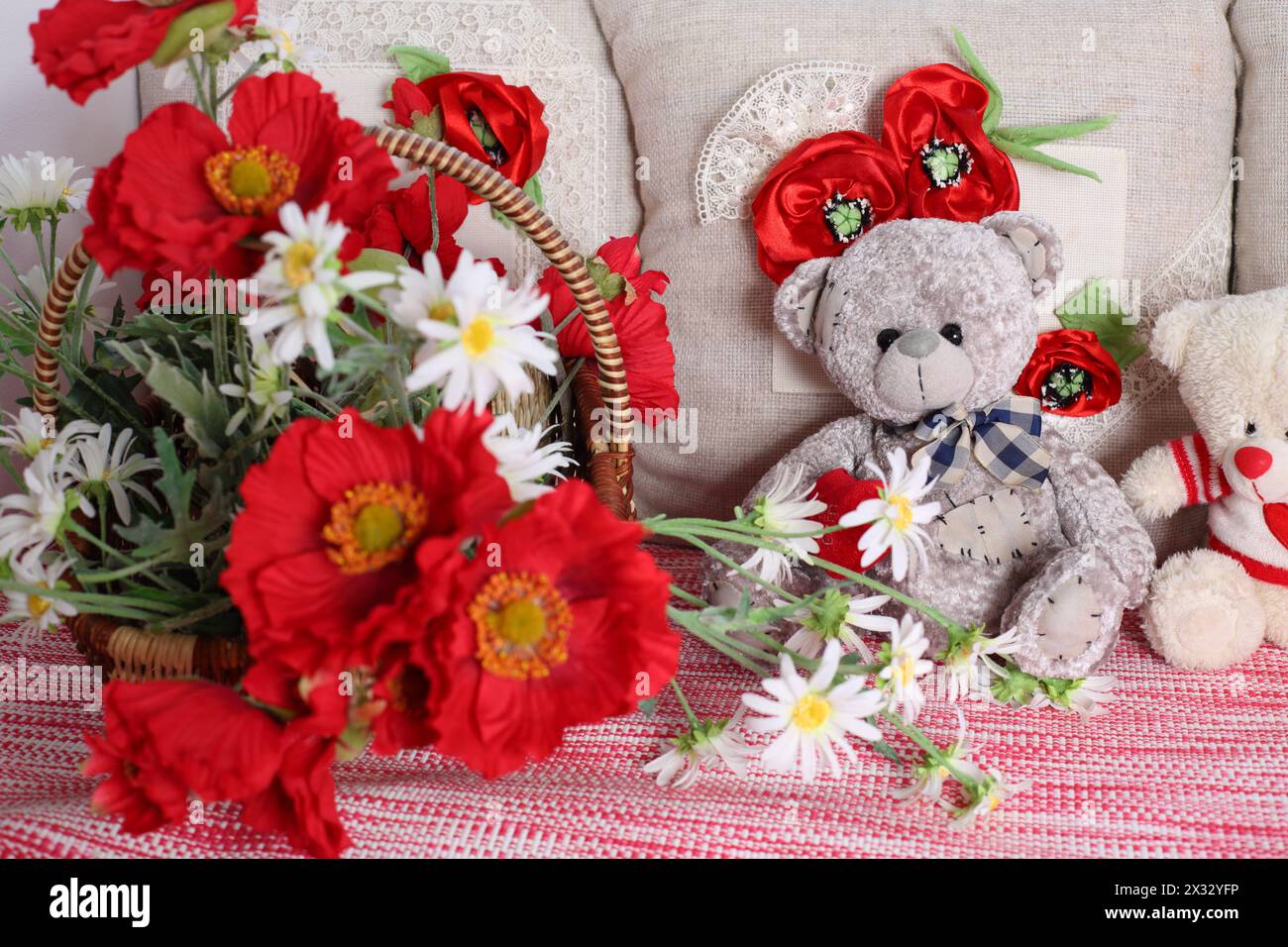 Basket with poppy and daisies, decorative pillows and teddy bears. Stock Photo