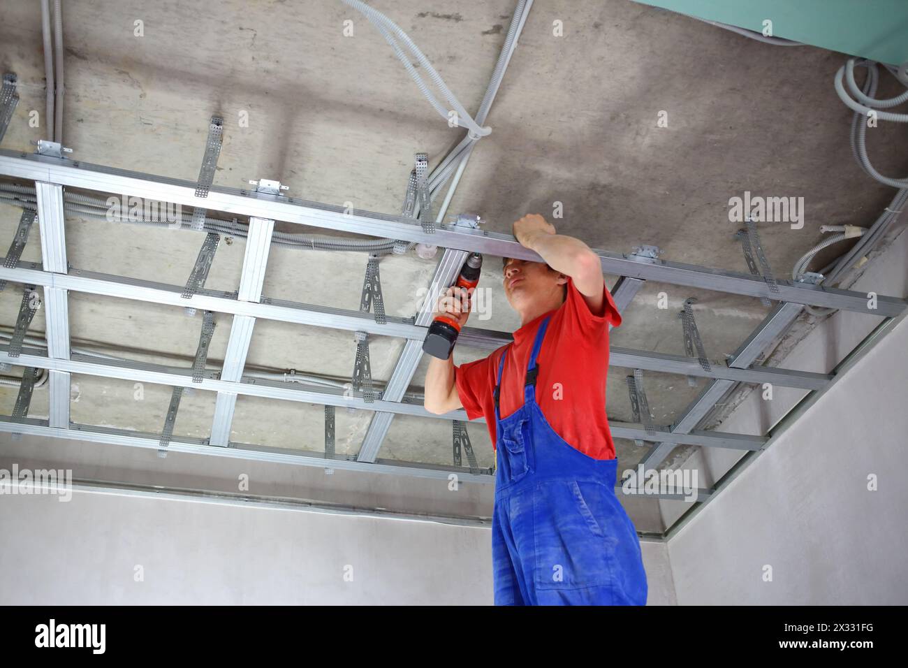 Worker fastens profile using cordless screwdriver Stock Photo