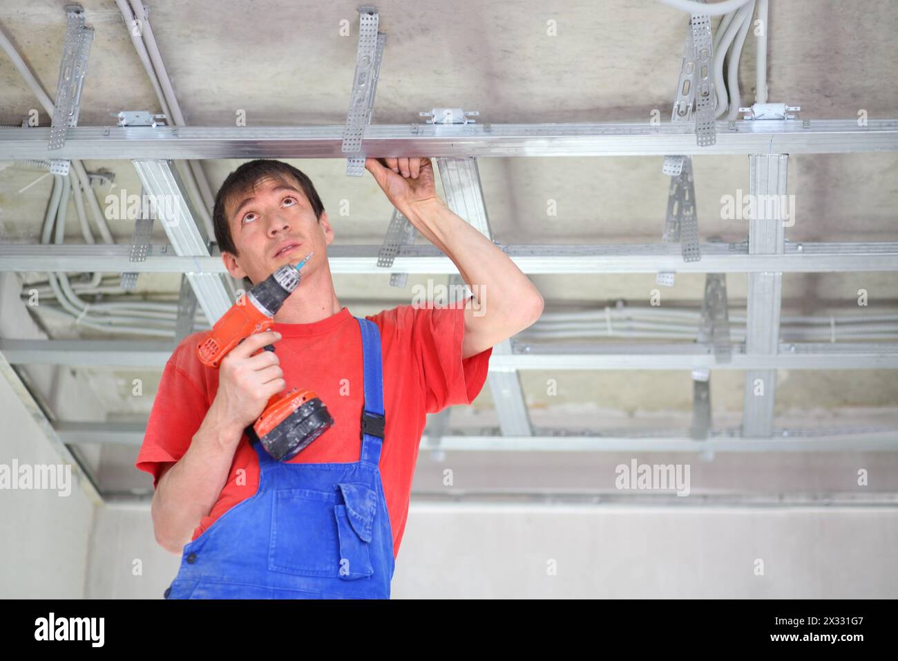 Builder fastens profile using cordless screwdriver Stock Photo