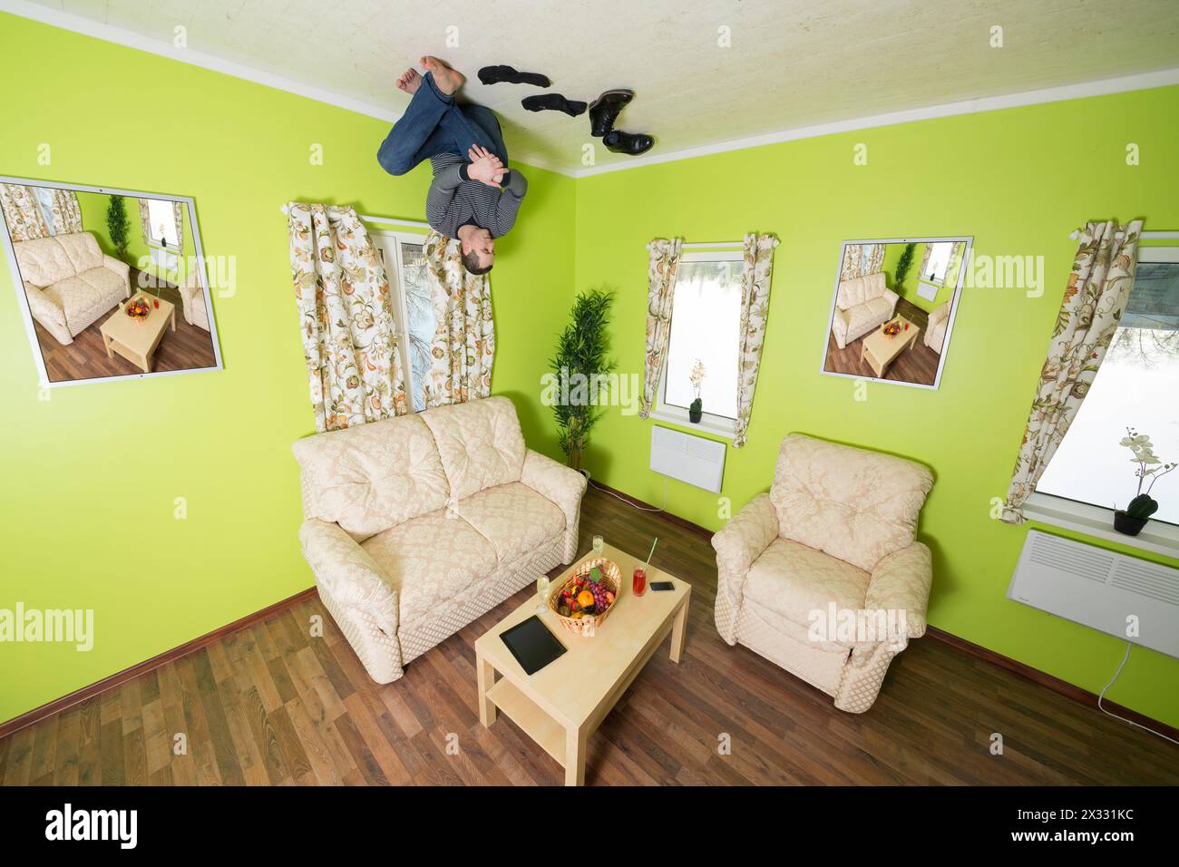 Man in jeans sitting on the ceiling without shoes and socks Stock Photo