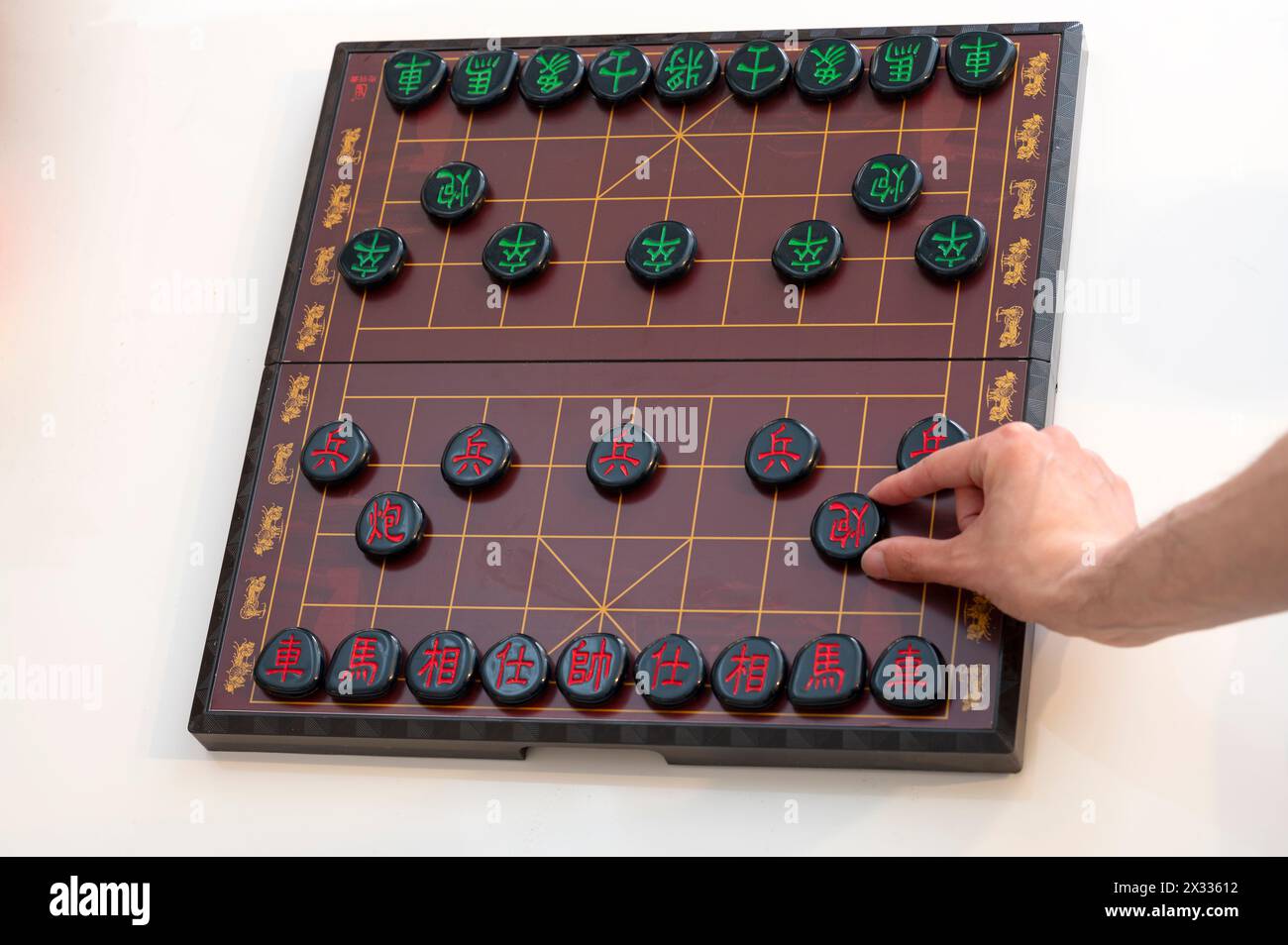 View of a Xiangqi board (Chinese chess) with a hand at the cannon piece Stock Photo