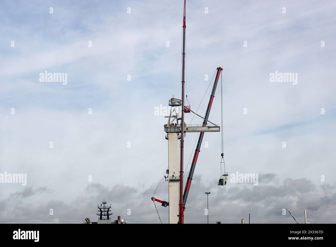 Men at work demolishing a large crane at Devonport Dockyard beside the River Tamar. Some on the crane itself and others in a cage suspended from anoth Stock Photo