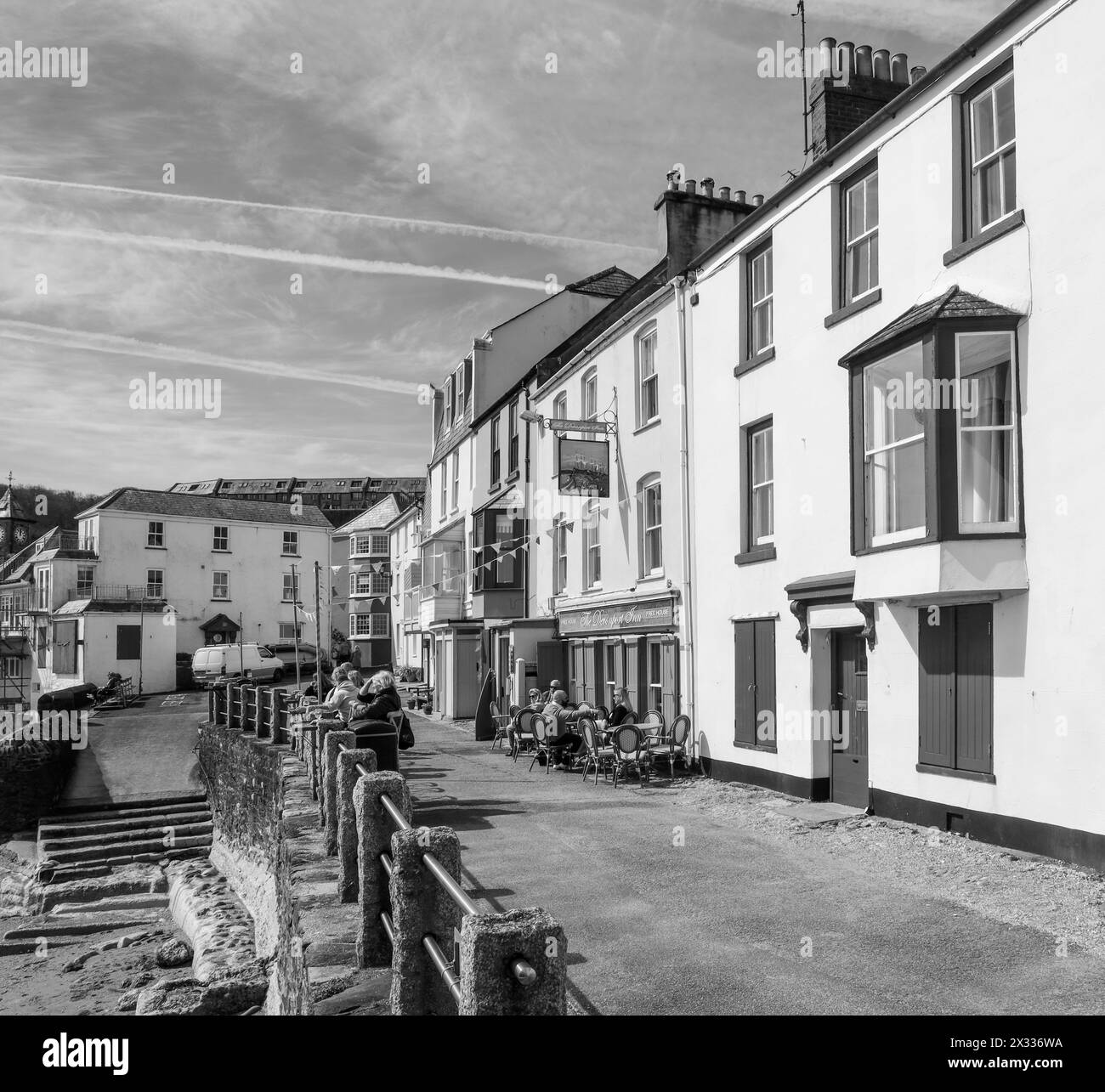 The Cleave at Kingsand on the Rame Peninsula. Vistors enjoy spring sunshine outside of the Devonport Inn. Monochrome image. Stock Photo