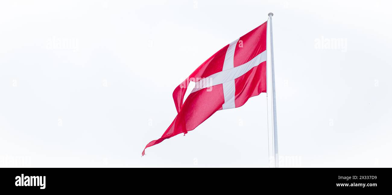 Flag of Denmark on white cloudy sky background. Stock Photo