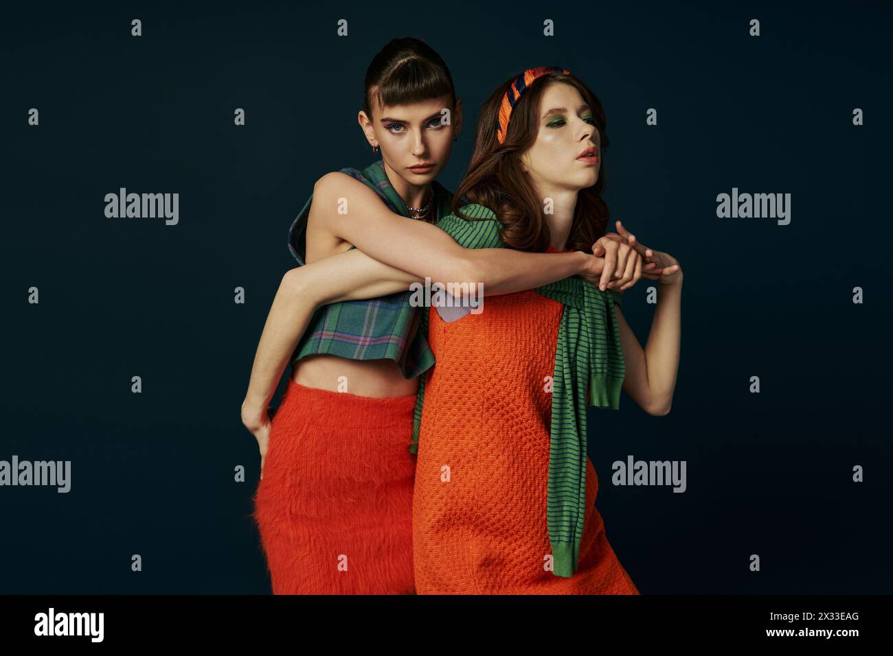 Two women in orange skirts hugging affectionately. Stock Photo