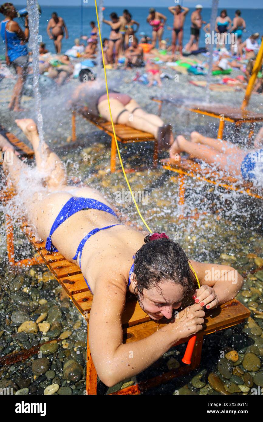 Woman on a lounger takes hydromassage shower on the beach Stock Photo