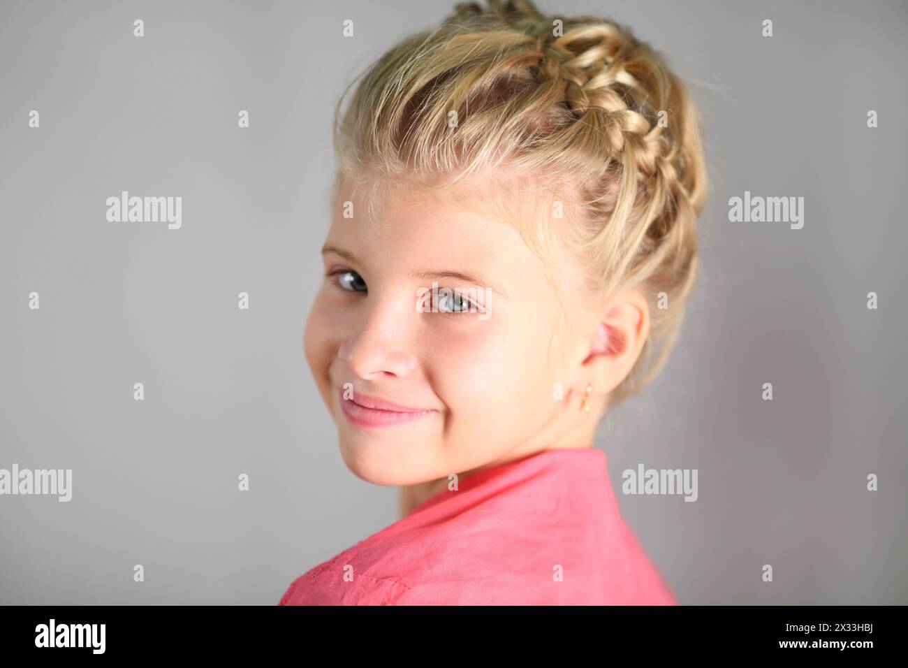 Portrait of a little girl with a pigtail on her head isolated on gray Stock Photo