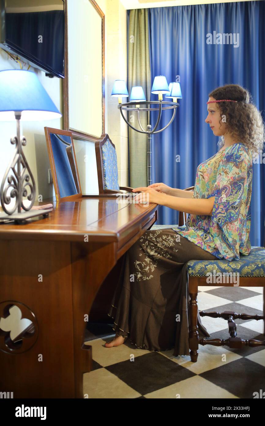 Woman in ethnic dress sitting at her dressing table in front of a mirror Stock Photo