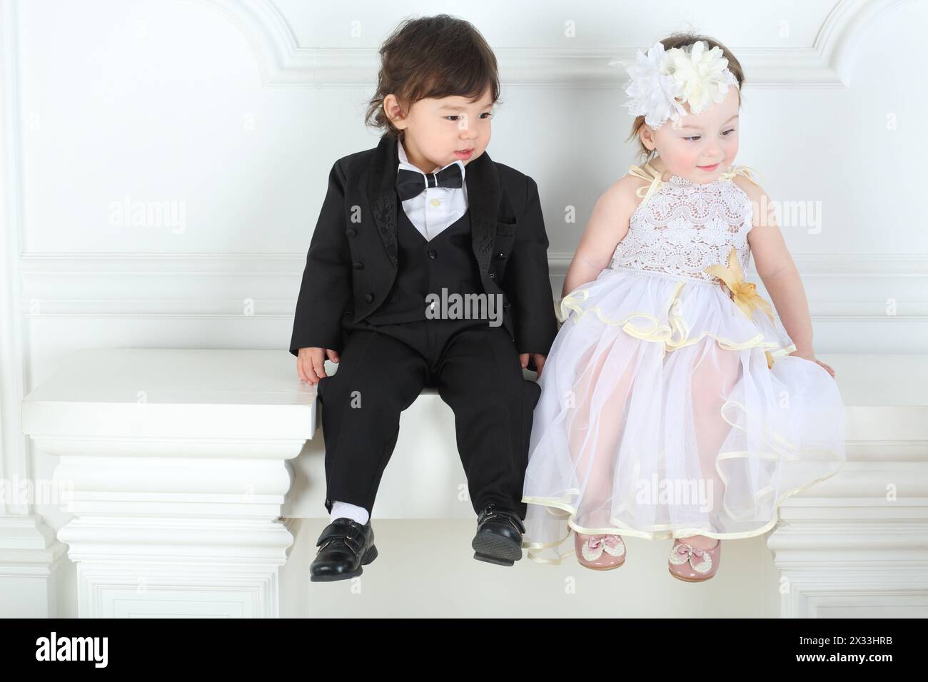 Beautiful little girl in white long dress with boy in a black tuxedo ...
