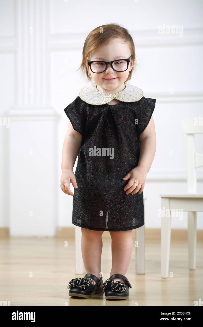 Portrait of smiling little girl in black dress and glasses Stock Photo ...