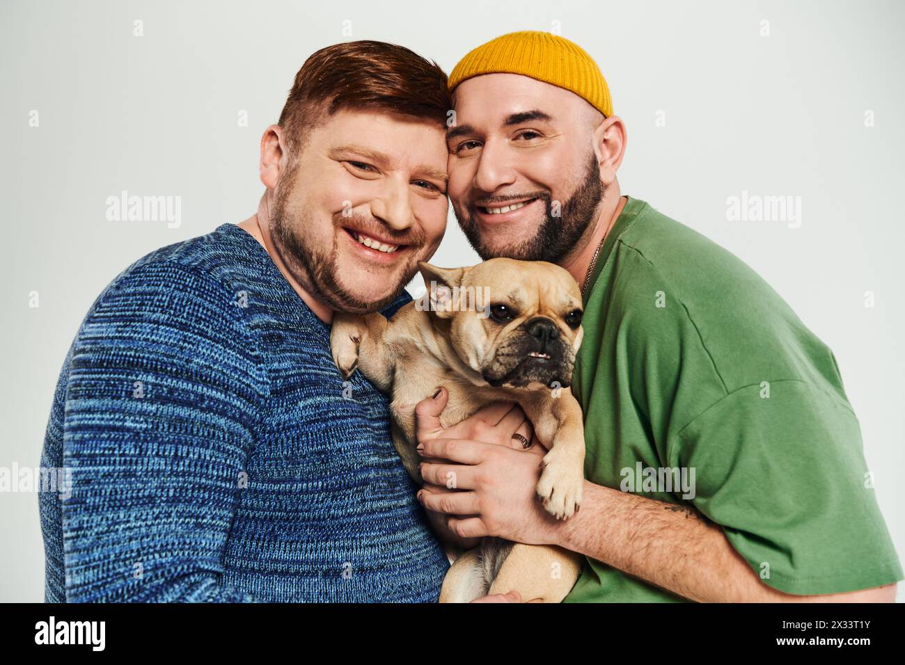 Two men hug tenderly, holding a small dog together. Stock Photo