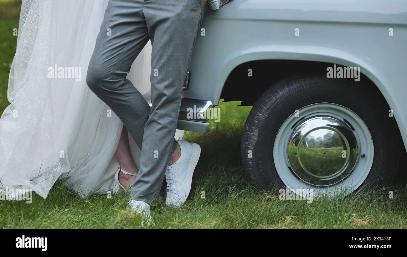 The bride and groom pose by a retro car on their wedding day Stock ...