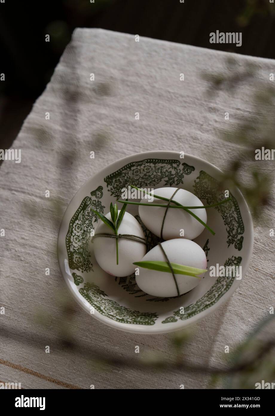 Easter. Three white decorated eggs in a green bowl on a beige background, shot from above. Stock Photo