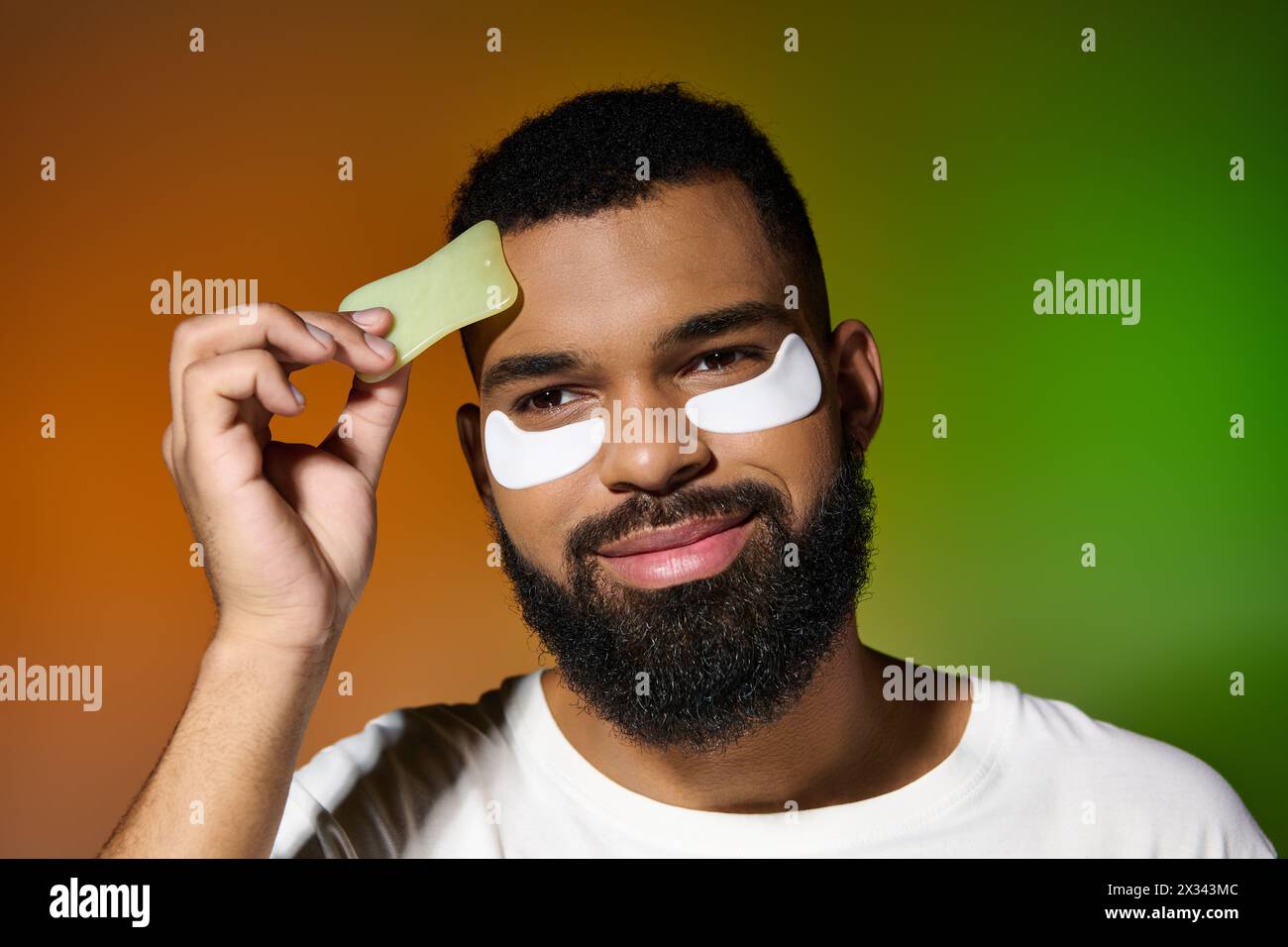 A man with a beard and eye patches on his face, engaging in skin care routine. Stock Photo