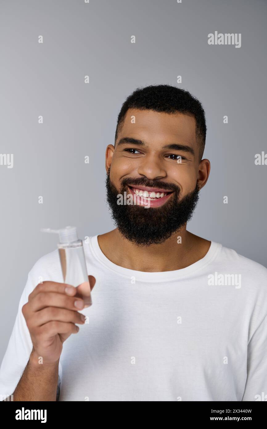 Handsome man with a beard holding a tube of locion. Stock Photo