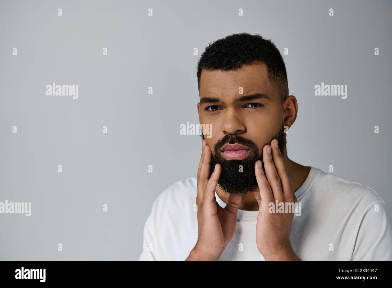 Handsome man with beard savoring his skincare routine. Stock Photo
