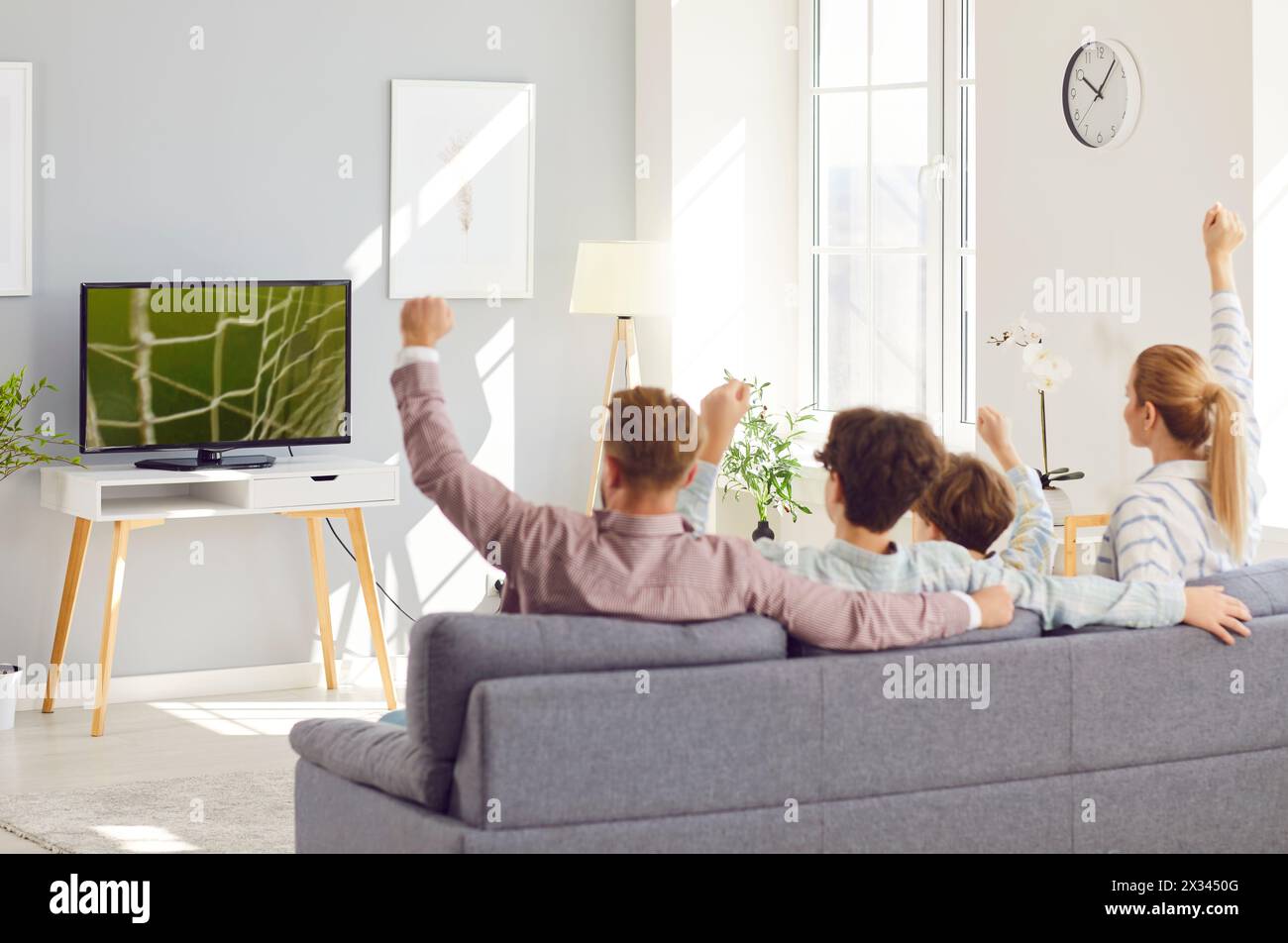 Family Watching Soccer Match on TV and Celebrating Team Goal Stock Photo