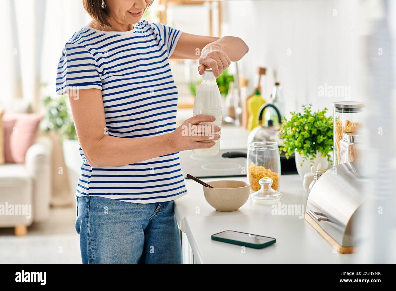 A woman in cozy homewear, standing in a kitchen, preparing food. Stock Photo