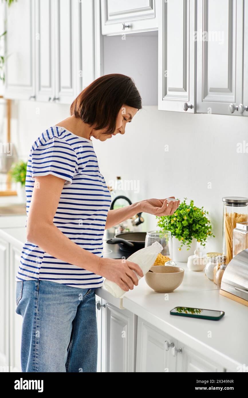 A woman in cozy attire stands in a kitchen, preparing food with focus and skill. Stock Photo