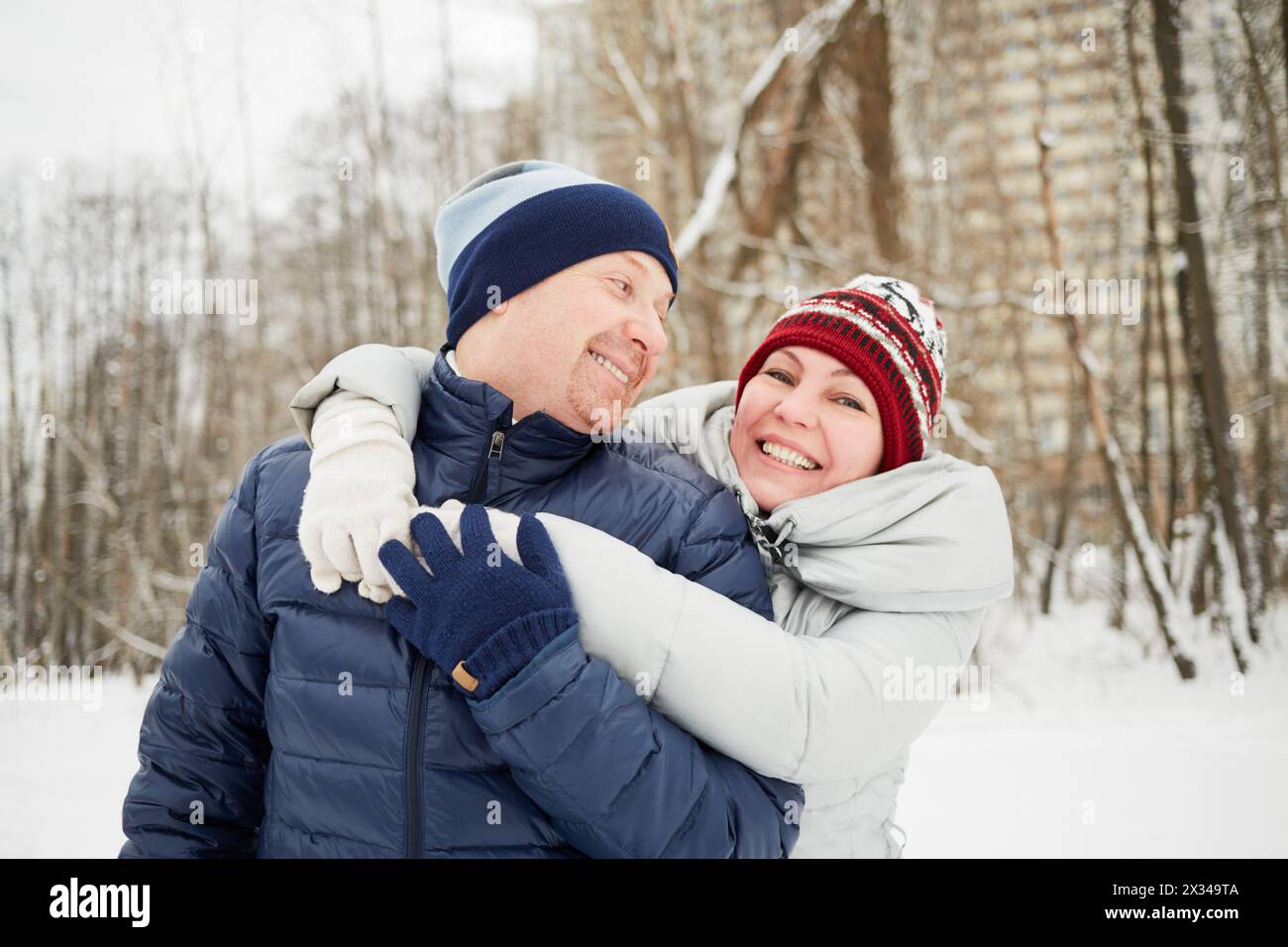 Half-length portrait of embracing smiling man and woman in winter park. Stock Photo