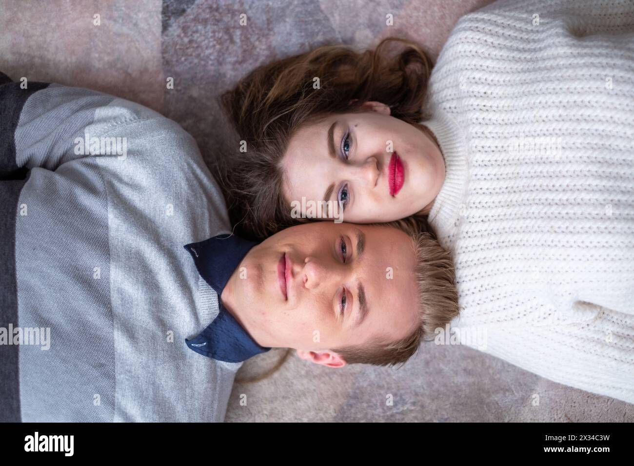 Relaxed duo in casual attire sharing a close, serene moment on the floor, embodying a sense of security and mutual affection. Suitable for themes of r Stock Photo