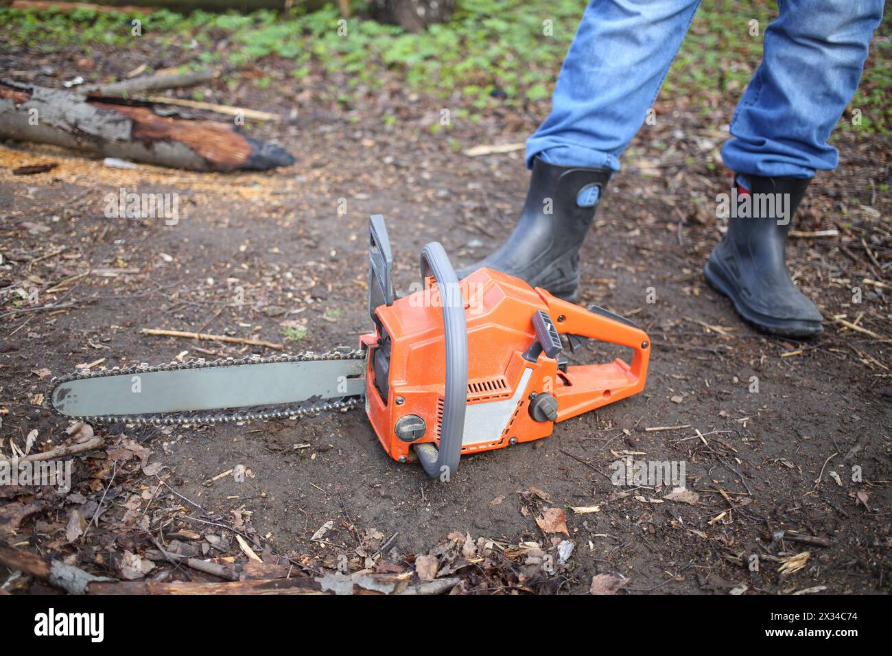 Chainsaw lying on the ground at the feet of men in rubber boots Stock ...