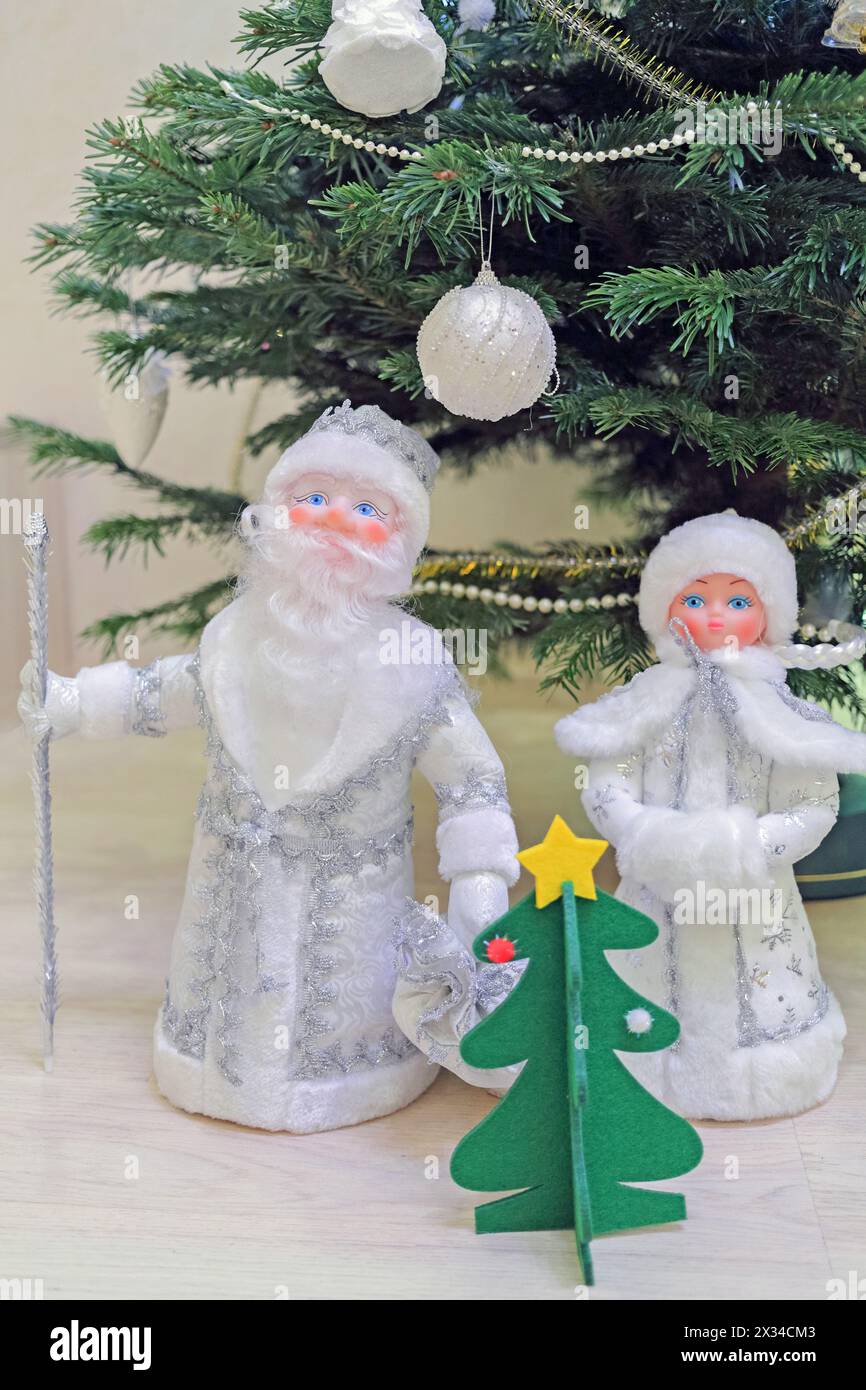 toy statuettes Snow Maiden, father frost and  small christmas tree under new year tree, close-up Stock Photo