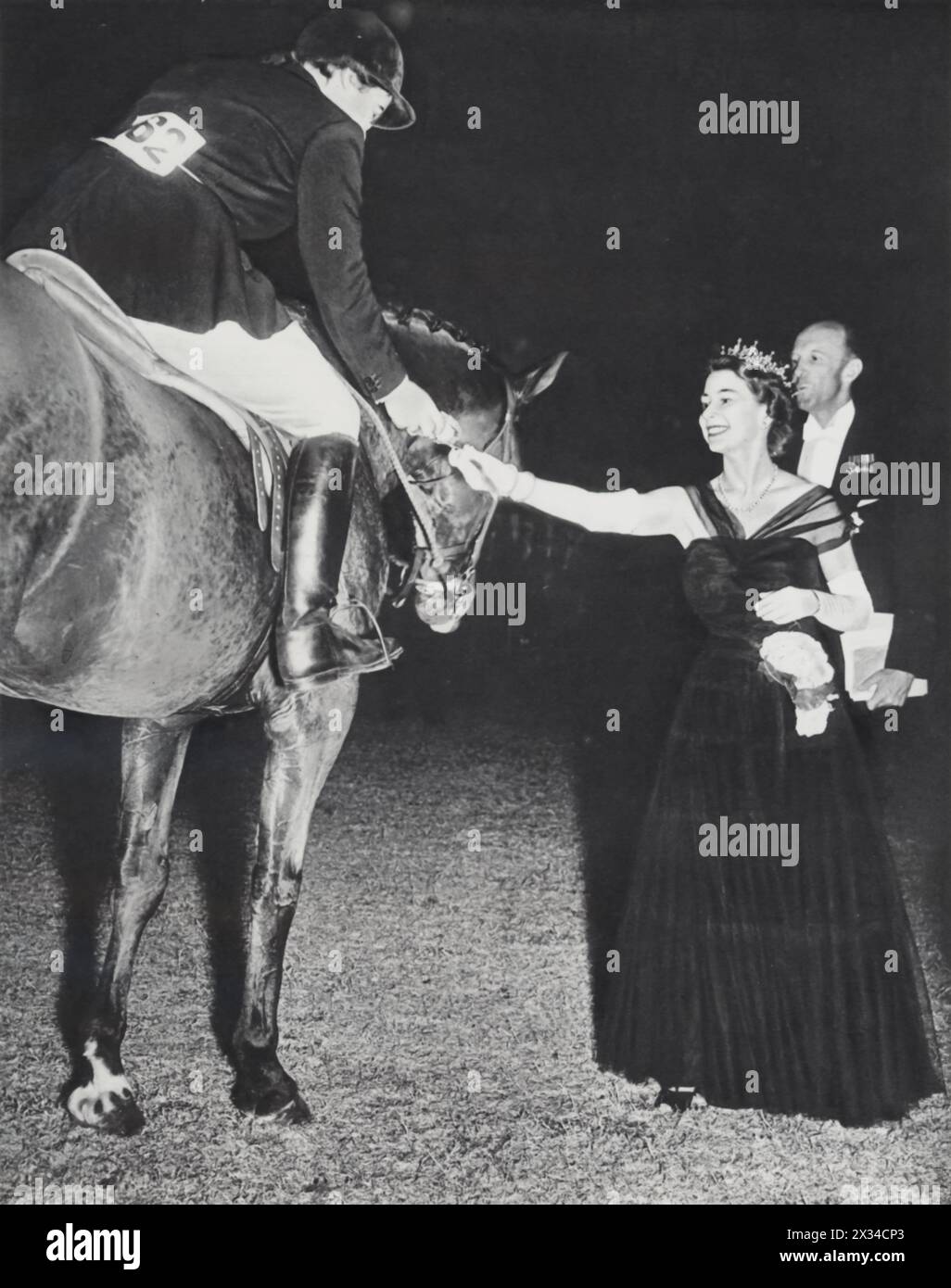 Queen Elizabeth II is captured at the Windsor Horse Show in July 1952, presenting a rosette to horse rider Patricia Ann Moss for her victory in the Ladies versus Gentleman Team Jumping Championship. Known for her love of horses, Elizabeth frequently attended horse shows. Patricia Ann Moss later distinguished herself as one of the most successful female rally drivers of all time. Stock Photo