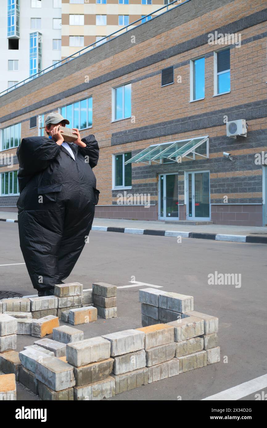 boy in black suit inflatable building brick wall in parking area near house Stock Photo