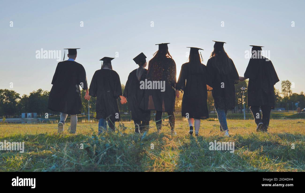 Graduate students walking through an evening meadow at sunset. Stock Photo