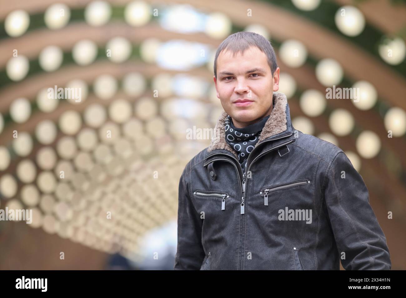 half length portrait of young man in black jacket on background of lights installation main park alley Stock Photo