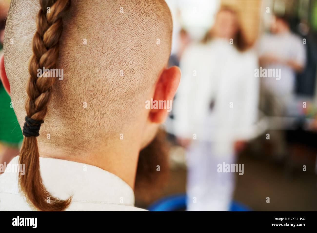 Back of the head of young man with shaved head and braided plait. Stock Photo