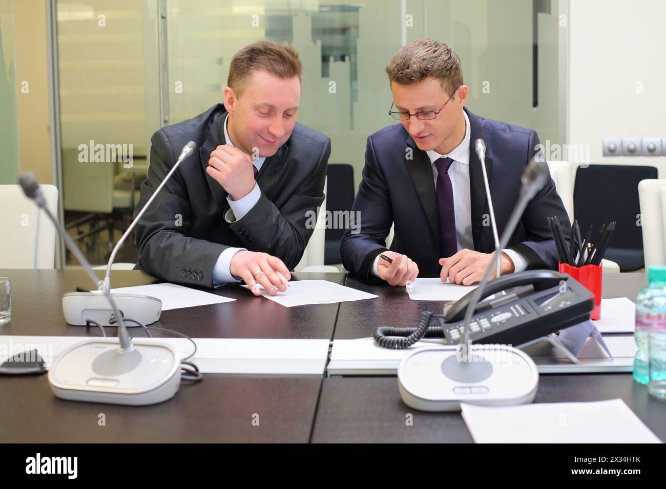 Two businessmen sitting at the table discussing documents Stock Photo