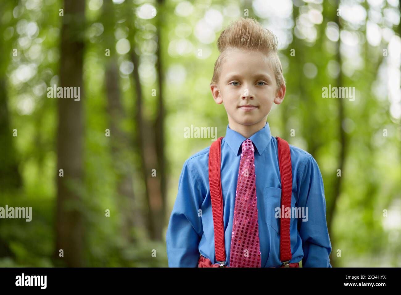 Portrait of boy wearing red trousers with braces, blue shirt, red tie ...