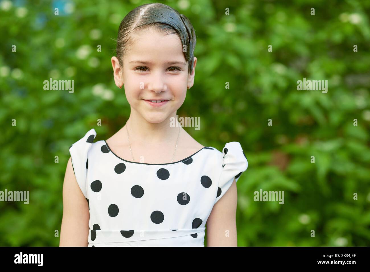 Half-length portrait of smiling little girl dressed in polka-dotted gown. Stock Photo