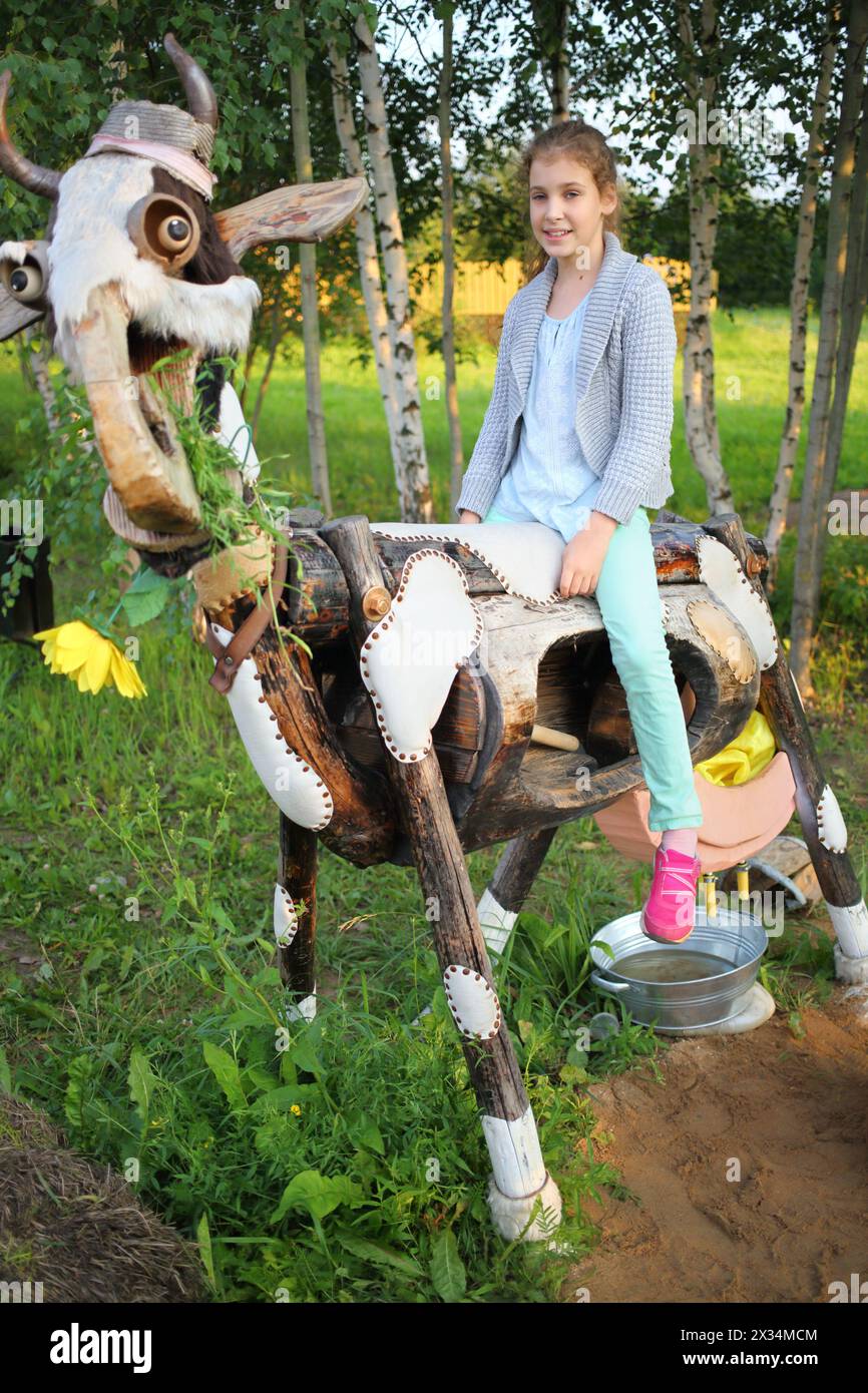A girl sits astride a stylized cow from exposure in Russian park Stock Photo